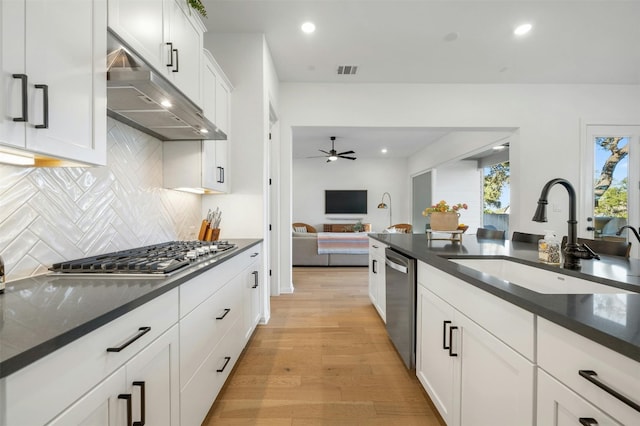 kitchen with tasteful backsplash, stainless steel appliances, sink, light hardwood / wood-style flooring, and white cabinetry