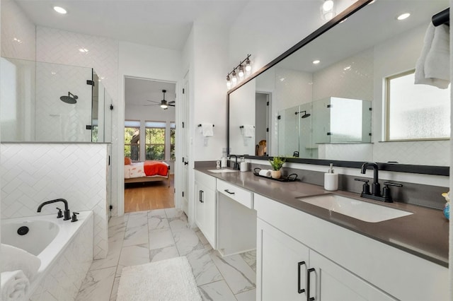 bathroom with plus walk in shower, wood-type flooring, vanity, and ceiling fan