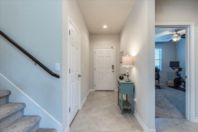 foyer entrance featuring ceiling fan and light carpet