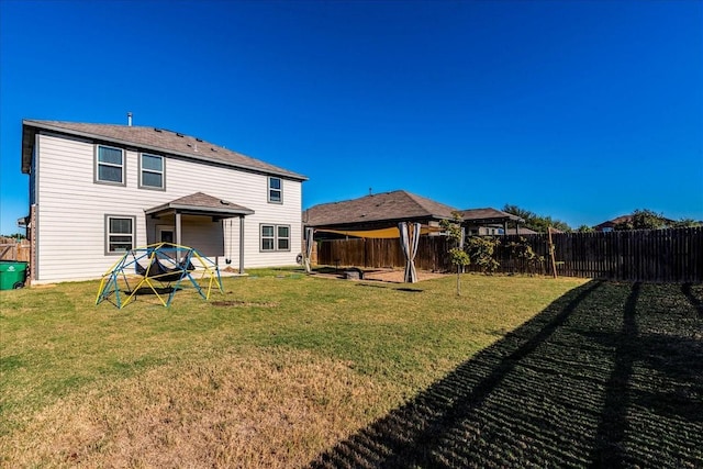 rear view of property featuring a yard and a gazebo