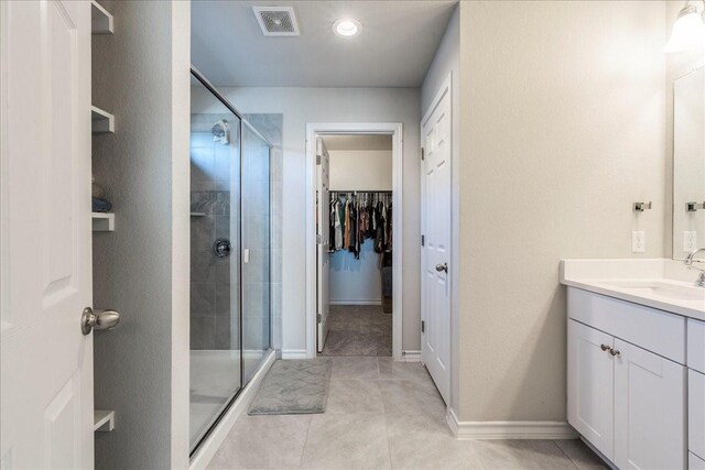 bathroom featuring a shower with door, tile patterned floors, and vanity