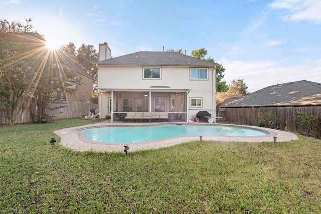 rear view of property featuring a sunroom, a fenced in pool, and a lawn