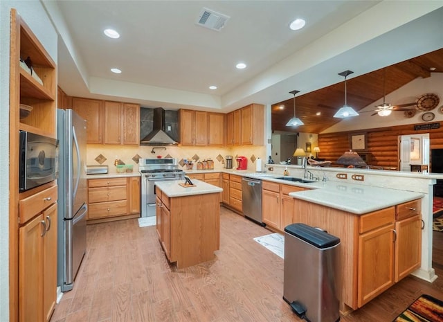 kitchen featuring sink, appliances with stainless steel finishes, a kitchen island, kitchen peninsula, and wall chimney exhaust hood