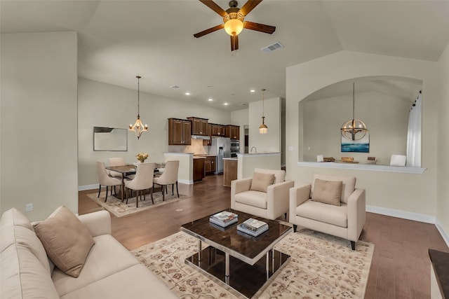 living room featuring hardwood / wood-style floors, ceiling fan with notable chandelier, and vaulted ceiling