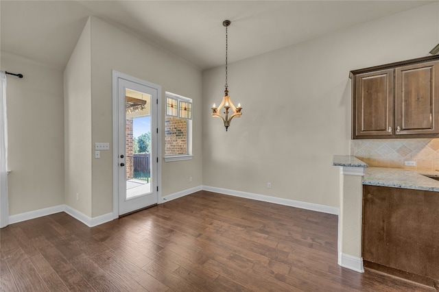 unfurnished dining area featuring dark hardwood / wood-style floors and an inviting chandelier