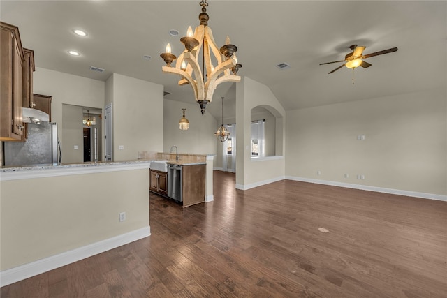 kitchen featuring ceiling fan with notable chandelier, light stone countertops, appliances with stainless steel finishes, dark hardwood / wood-style flooring, and kitchen peninsula