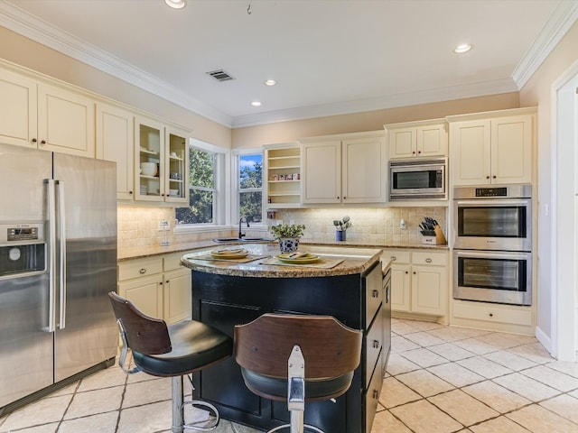 kitchen with a center island, light stone countertops, ornamental molding, light tile patterned flooring, and stainless steel appliances