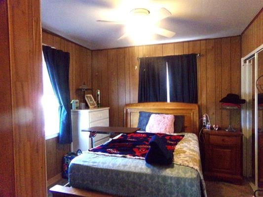 bedroom featuring ceiling fan and wood walls