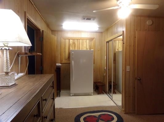 kitchen with wood walls, light carpet, white refrigerator, ceiling fan, and butcher block counters