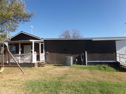 back of house featuring a lawn and central air condition unit