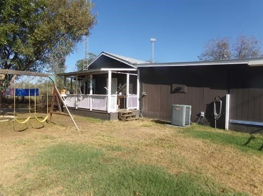 back of house featuring a yard, a playground, and central AC unit