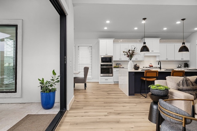 kitchen with decorative light fixtures, built in microwave, white cabinets, decorative backsplash, and stainless steel oven