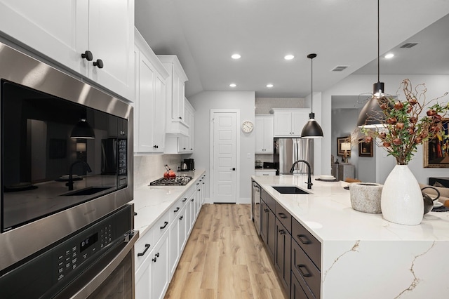 kitchen featuring pendant lighting, sink, white cabinetry, stainless steel appliances, and light stone countertops