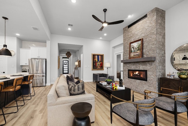 living room with ceiling fan, a fireplace, and light hardwood / wood-style floors