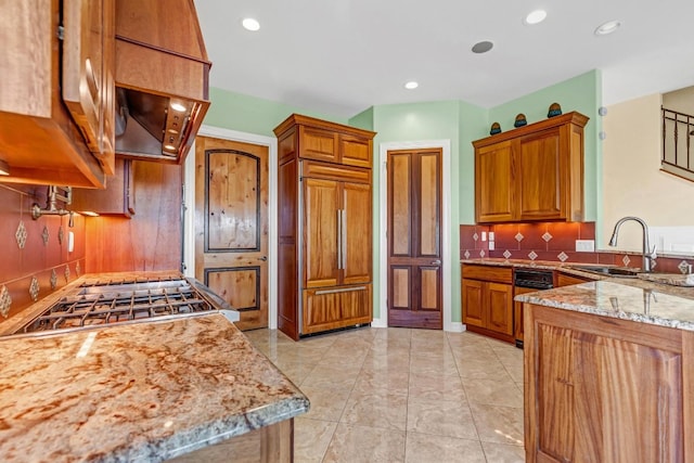 kitchen featuring decorative backsplash, paneled built in fridge, light stone counters, and sink