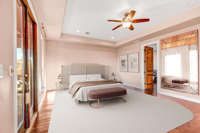 bedroom featuring a tray ceiling, ceiling fan, and dark hardwood / wood-style flooring