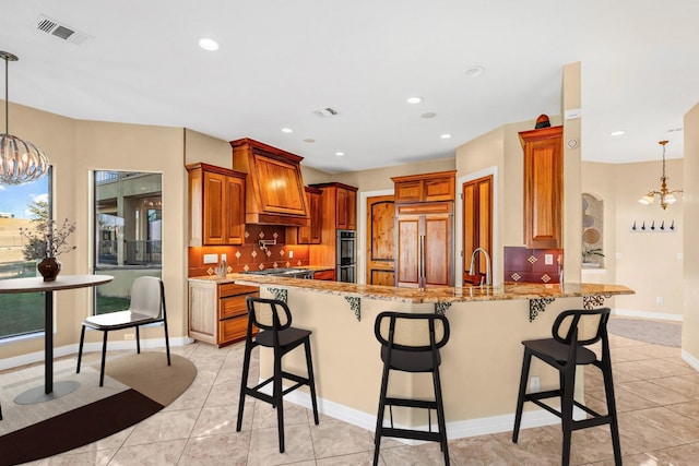 kitchen with pendant lighting, an inviting chandelier, paneled refrigerator, light stone counters, and kitchen peninsula