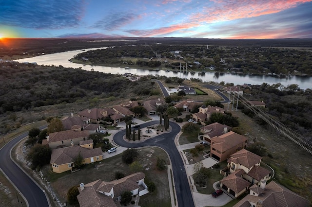 aerial view at dusk featuring a water view