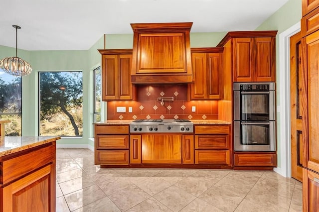 kitchen featuring light stone countertops, hanging light fixtures, an inviting chandelier, tasteful backsplash, and appliances with stainless steel finishes