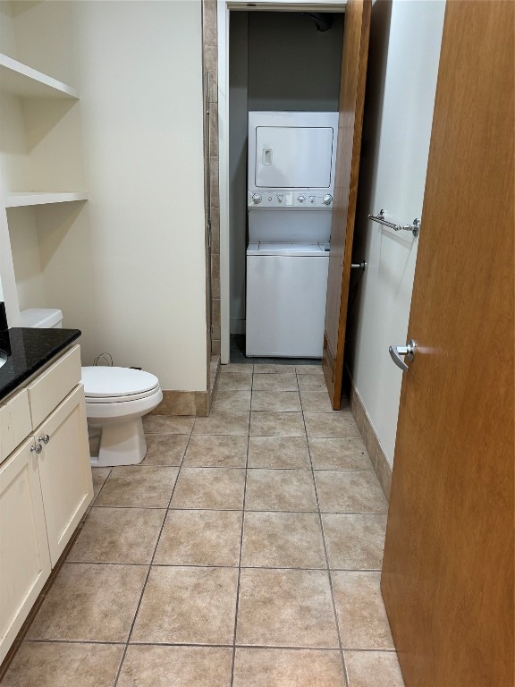 bathroom featuring tile patterned floors, stacked washer / drying machine, toilet, and vanity