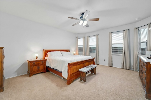 bedroom featuring ceiling fan, light colored carpet, and multiple windows