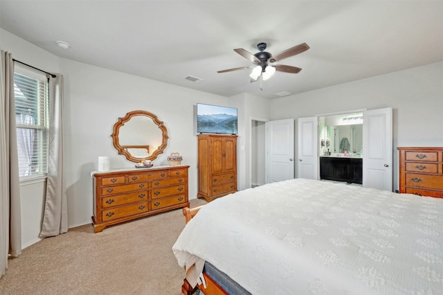 bedroom with ensuite bathroom, ceiling fan, and light carpet