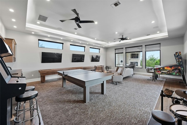 game room featuring ceiling fan, wood-type flooring, and a tray ceiling