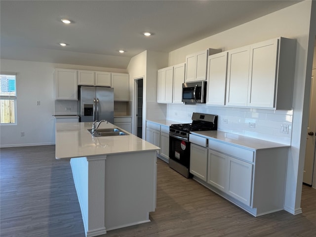 kitchen with a center island with sink, white cabinets, sink, dark hardwood / wood-style flooring, and stainless steel appliances