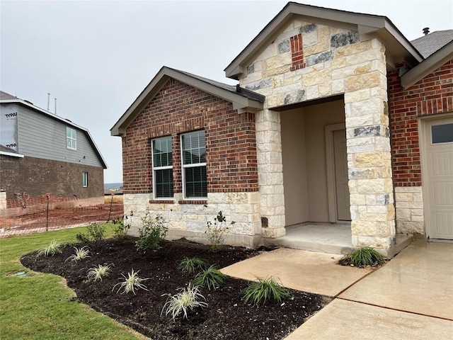 exterior space featuring a garage, stone siding, and brick siding