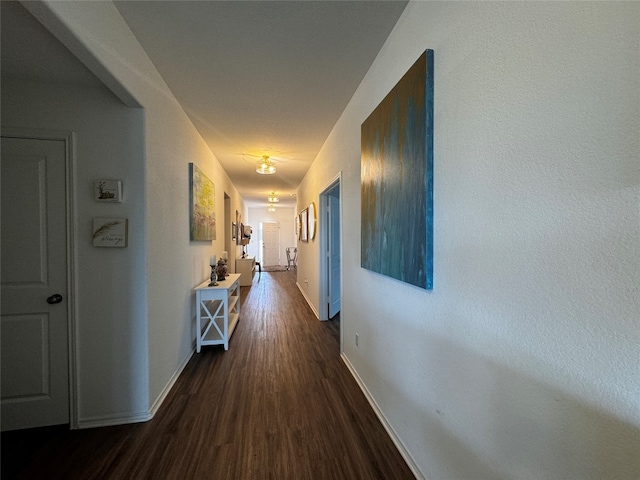 corridor with baseboards and wood finished floors