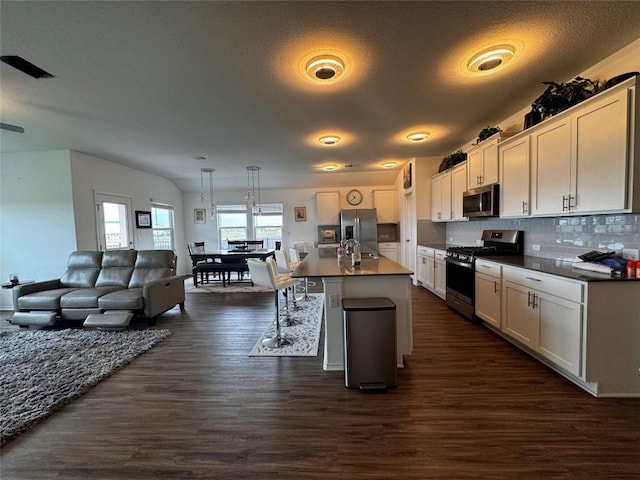 kitchen with appliances with stainless steel finishes, open floor plan, dark wood-type flooring, and decorative backsplash