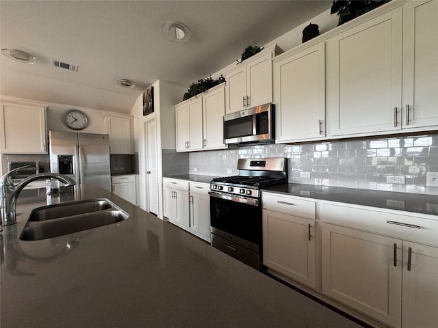 kitchen featuring stainless steel appliances, a sink, visible vents, white cabinets, and tasteful backsplash