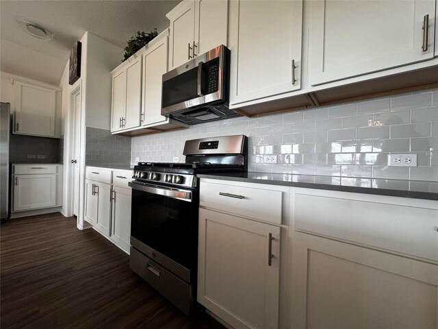 kitchen featuring dark countertops, dark wood finished floors, stainless steel appliances, and decorative backsplash