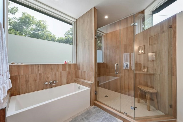 bathroom featuring separate shower and tub and tile walls