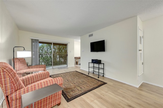 living room featuring a textured ceiling and light hardwood / wood-style floors