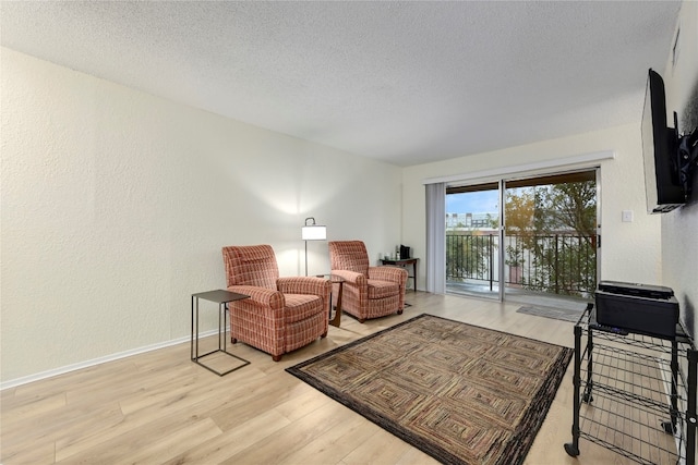 living area with a textured ceiling and light wood-type flooring