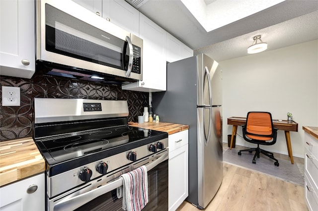 kitchen featuring butcher block counters, white cabinets, stainless steel appliances, and light wood-type flooring