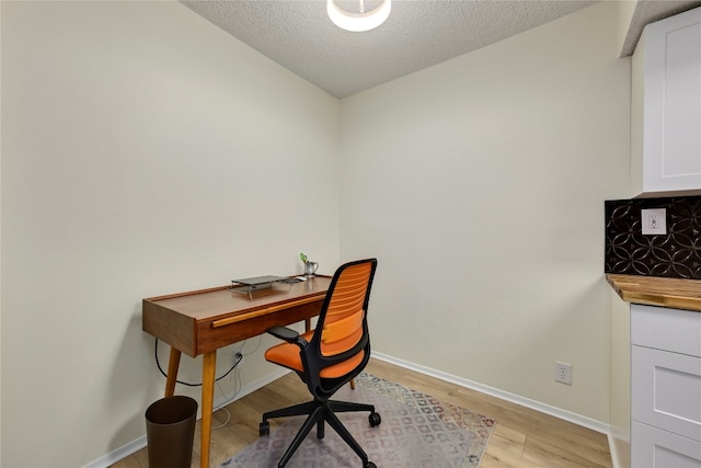 home office with a textured ceiling and light hardwood / wood-style flooring