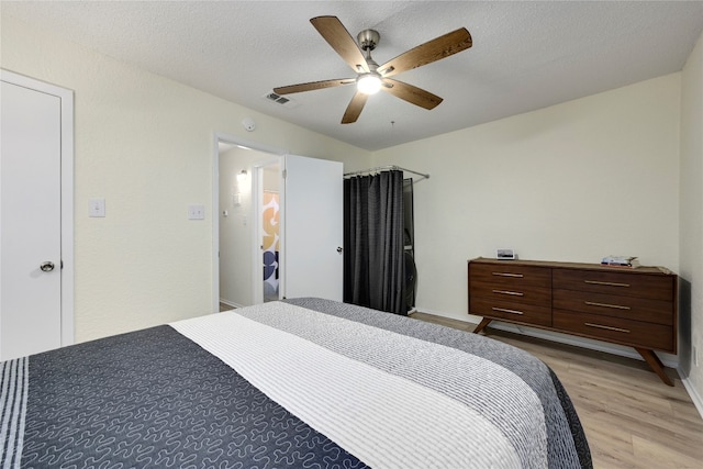 bedroom with ceiling fan, light wood-type flooring, and a textured ceiling