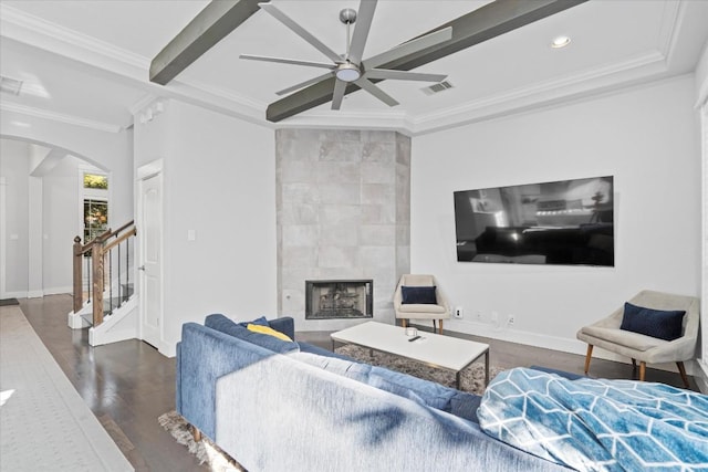 1503 Juliet St, Austin, TX 78704 - living room featuring arched walkways, a ceiling fan, ornamental molding, a tiled fireplace, and dark wood finished floors