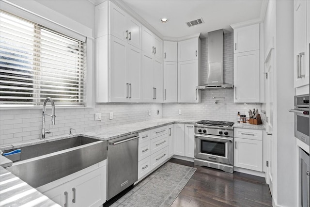 1503 Juliet St, Austin, TX 78704 - kitchen featuring stainless steel appliances, wall chimney exhaust hood, plenty of natural light, white cabinets, and recessed lighting