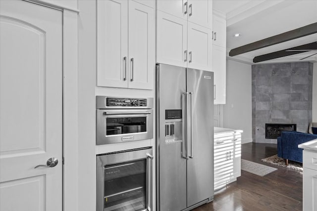 1503 Juliet St, Austin, TX 78704 - kitchen featuring stainless steel appliances, wine cooler, dark wood-style floors, a fireplace, and white cabinets