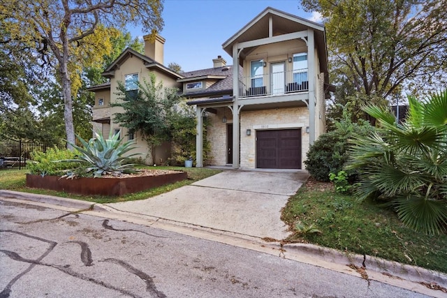 1503 Juliet St, Austin, TX 78704 - view of front facade featuring an attached garage, a balcony, a chimney, driveway, and stone siding