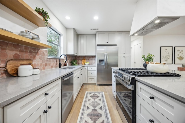 kitchen featuring light stone counters, sink, stainless steel appliances, and custom range hood