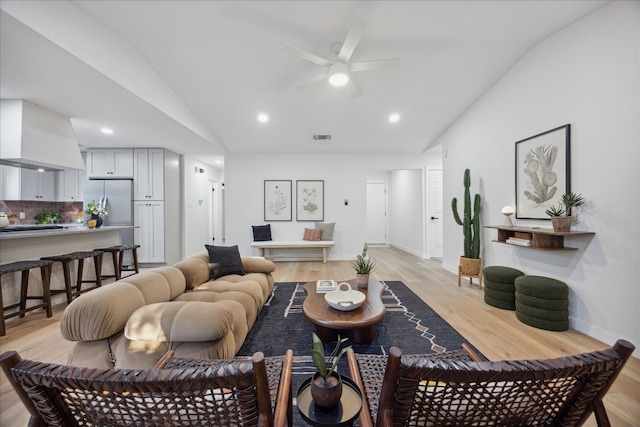 living room with light hardwood / wood-style floors, vaulted ceiling, and ceiling fan