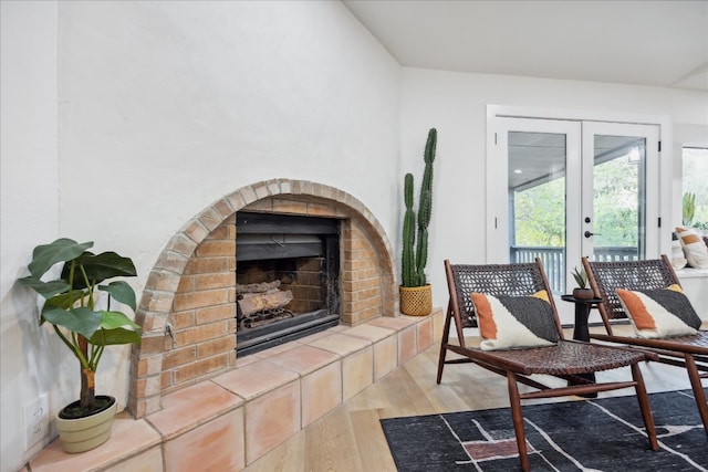 sitting room with a tile fireplace, french doors, and light wood-type flooring