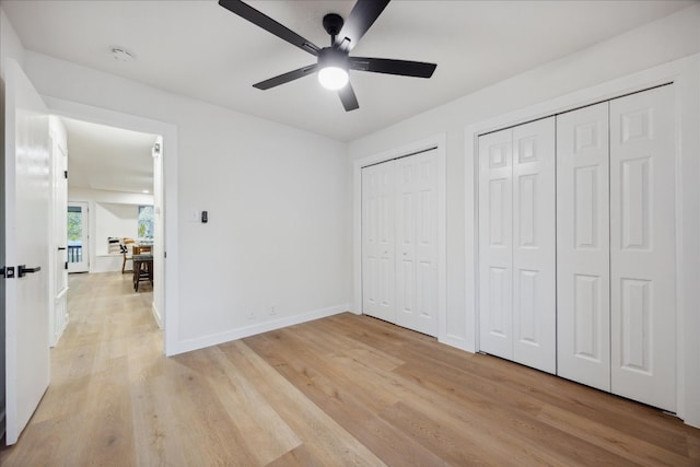 unfurnished bedroom featuring ceiling fan, two closets, and light hardwood / wood-style flooring