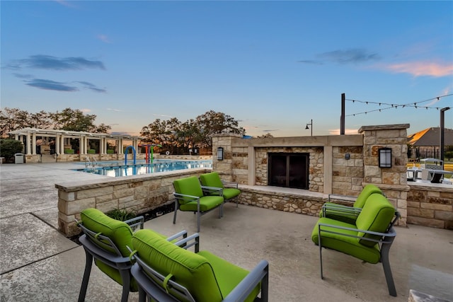 patio terrace at dusk featuring a pergola and a community pool