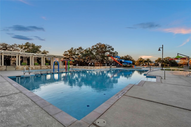 pool at dusk with a patio and a water slide