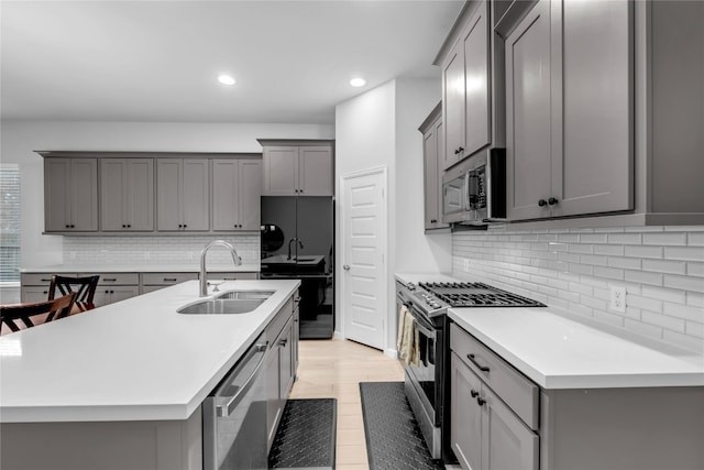 kitchen with gray cabinetry, sink, stainless steel appliances, and tasteful backsplash